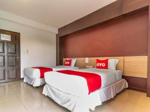 two beds in a hotel room with red pillows at OYO 1127 Baan Siam Hotel in Chiang Rai