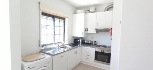 a kitchen with white cabinets and a sink and a window at APC Apartamento Palmela Village in Palmela