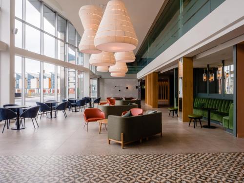 a lobby with chairs and tables and windows at Apex City Quay Hotel & Spa in Dundee