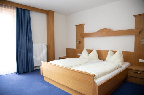 a bedroom with a large wooden bed with white pillows at Erlebnishotel Kärnten-Mölltal 3 Stern Superior in Obervellach