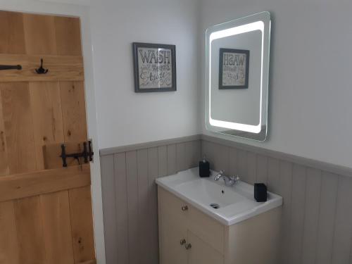 uma casa de banho com um lavatório e um espelho em Riverside em Skeabost