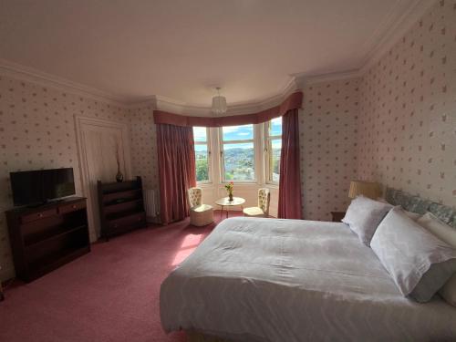 een slaapkamer met een groot bed en een televisie bij Dunrigh Guest House in Oban