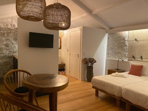 a bedroom with a bed and a table and a tv at LUZZ me - Casas de Santa Bárbara in Santa Bárbara