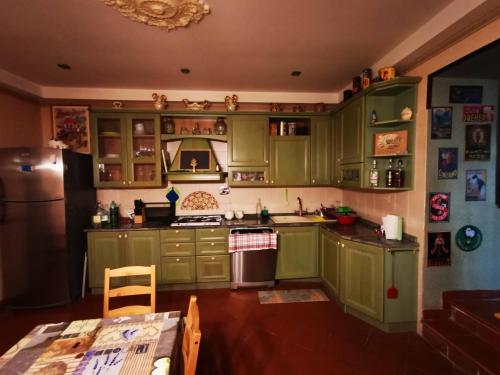 eine Küche mit grünen Schränken, einem Tisch und einem Kühlschrank in der Unterkunft La suite del Cardinale in Montefiascone