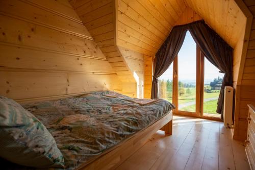 a bed in a wooden room with a large window at Domek Nad Doliną in Orawka