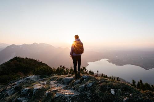 a person standing on top of a mountain looking at the sunset at aja Garmisch-Partenkirchen in Garmisch-Partenkirchen