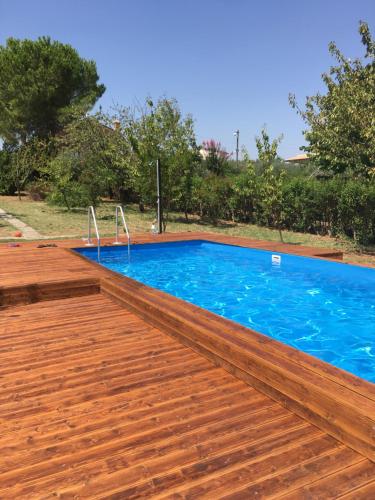 a swimming pool with a wooden deck and blue water at La villa più bella con piscina in Treglio