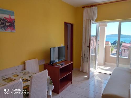 a living room with a television and a balcony at Apartments Vodopija 300m to the beach in Sveti Filip i Jakov