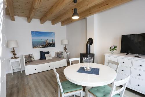 ein Wohnzimmer mit einem weißen Tisch und einem TV in der Unterkunft Hotel & Ferienunterkünfte Hus Seeblick in Fehmarn