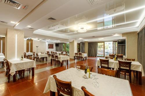 a dining room with white tables and chairs and tablesearcher at Lira Pacific Aparthotel in Constanţa