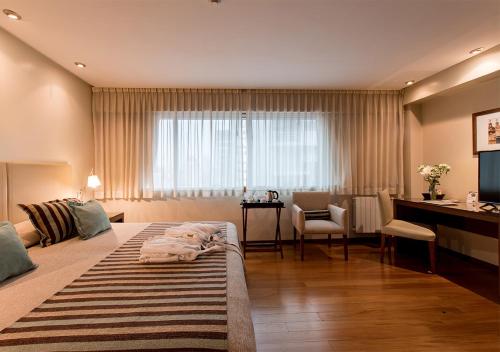 a bedroom with a large bed with a desk and a desk at Hotel Solans Presidente in Rosario