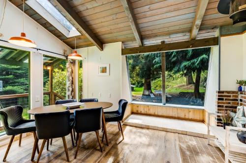 a dining room with a table and chairs and a large window at Tall Cedars Cabin By The Water in Eastsound