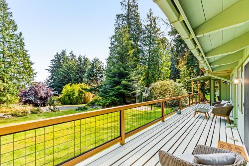 a deck with chairs and tables on a house at Tall Cedars Cabin By The Water in Eastsound