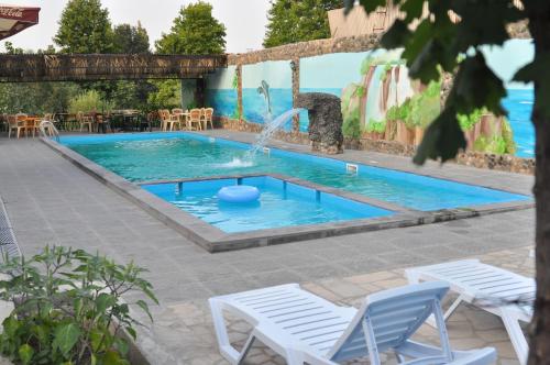 a pool with a fountain and two lawn chairs at Mayisyan Kamurj Hotel in Ijevan