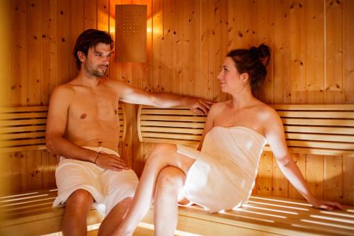 ein Mann und eine Frau sitzen in einer Sauna in der Unterkunft Hotel-Restaurant Allmer in Weiz
