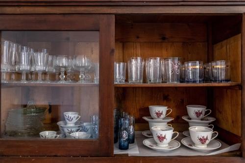 a cabinet filled with glasses and cups and saucers at The Aegean blue country house Old Milos in Lagoúdi Zía