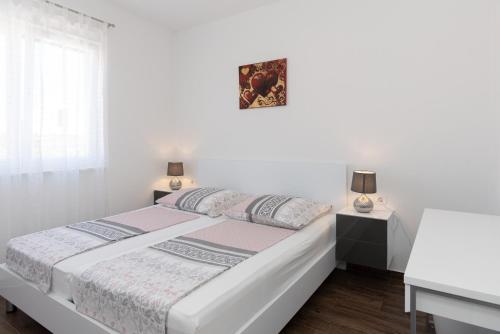 a white bedroom with a bed and two lamps at Luxury Apartment Lukas Pool & Parking Vodice in Vodice