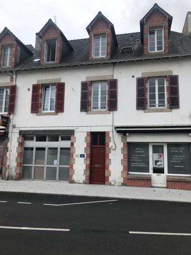 a white building with a red door on a street at Studio Duplex Bénodet in Bénodet