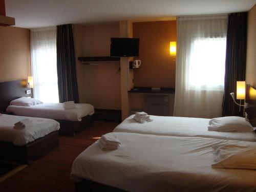 a hotel room with two beds and a television at Hôtel Inn Design Resto Novo Amiens in Dury