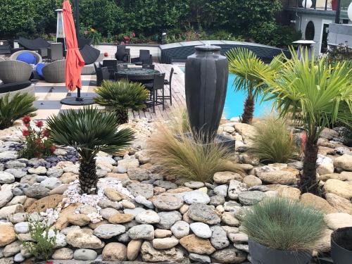 a garden with a pool and a large black vase at Hotel la piscine in Villers-sur-Mer