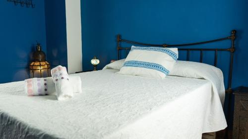 Dormitorio azul con cama con sábanas y almohadas blancas en Casas Triana, en Triana