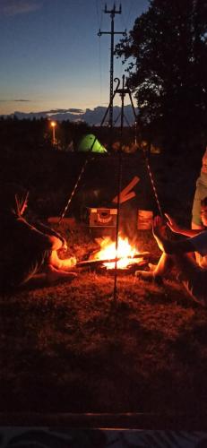 a person is sitting around a camp fire at Agroturystyka Pokój na Skarpie in Kowale Oleckie
