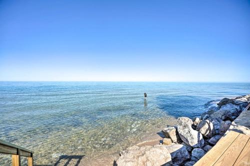 a person standing in the water at the beach at Modern Lake Michigan Home with 3 Lakefront Decks! in Holland