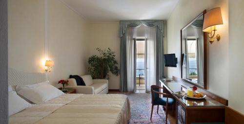 a hotel room with a bed and a desk with a mirror at Hotel Villa Capri in Gardone Riviera