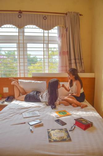 two girls are laying on a bed at Mui Tau Hotel Phan Ri Cua in Tuy Phong