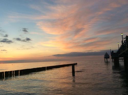a pier in the water with a cloudy sky at Am Horizont No 1 für 2-4 Pers, 2 Schlafz, Babybett, Südbalkon, kostenloser Parkplatz, 500 Meter zum Strand in Zingst