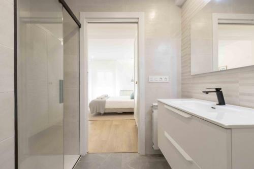 1 cama y baño con lavabo y ducha. en The Rentals Collection - Belvedere, en San Sebastián