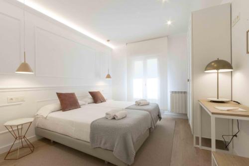 a white bedroom with a bed and a desk at The Rentals Collection - Belvedere in San Sebastián