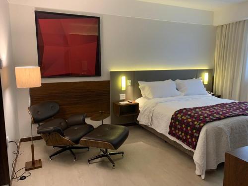 a bedroom with a bed, desk, chair and a lamp at Bugan Recife Hotel by Atlantica in Recife