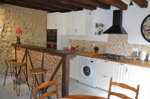 une cuisine avec des armoires blanches et un comptoir avec des tabourets dans l'établissement Le Pigeonnier, maison de charme au pied du château, à Amboise