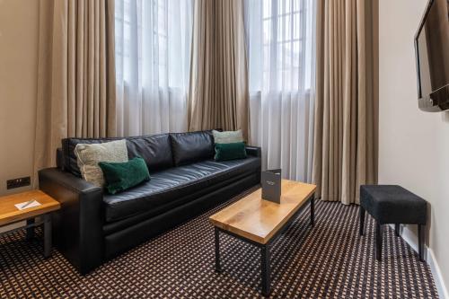 a living room with a black leather couch and a table at The Resident Liverpool in Liverpool