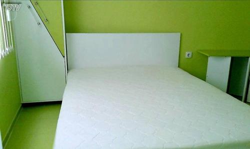 a large white bed in a green room at АПАРТАМЕНТ LEO 4 in Varna City