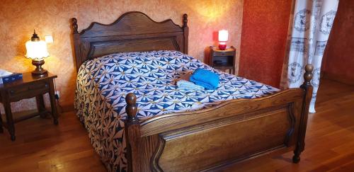 1 dormitorio con cama de madera y almohada azul en La mouche,chambres avec terrasse vue sur la rivière, en Humes