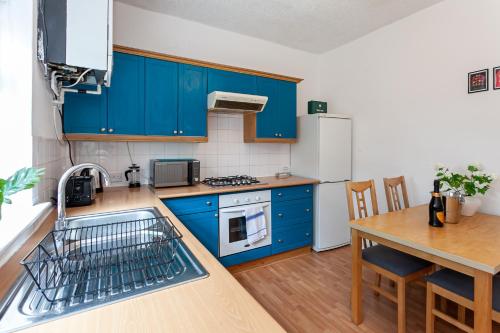 a kitchen with blue cabinets and a table at Chic 3 Bed House for up to 6 people in the city of Manchester in Manchester