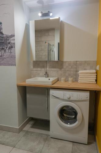 a bathroom with a washing machine and a sink at Moon Apartments Poznań in Poznań