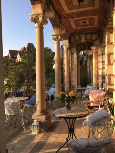 an outdoor patio with chairs and tables and columns at La Villa L'Argentine in Cabourg