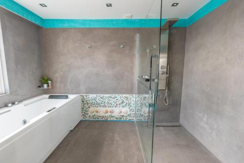a bathroom with a shower and a bath tub at The Waterside Designer Waterfront Oasis Spa & Sauna Terrace in Zwanenburg