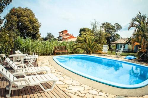 a swimming pool with white chairs and a table at Pousada Natural Park in Imbituba