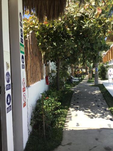 a sidewalk next to a building with trees and a fence at Casa Villamor in Máncora