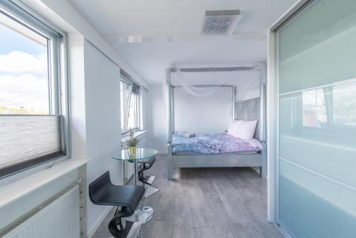 a small bedroom with a bed and a table and a chair at The Waterside Designer Waterfront Oasis Spa & Sauna Terrace in Zwanenburg