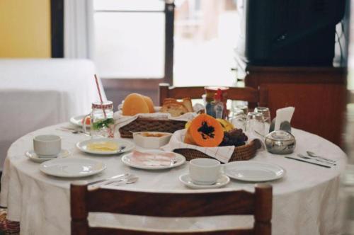 ein Tisch mit einer weißen Tischdecke und Essen darauf in der Unterkunft Pousada Beira Mar in Garopaba