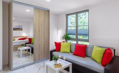 uma sala de estar com um sofá com almofadas vermelhas e verdes em Apartmán B Harrachov em Harrachov