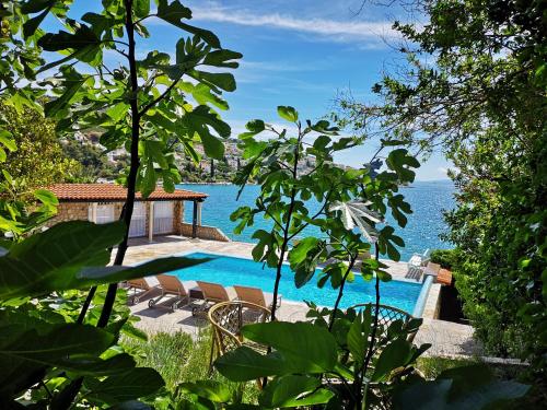 einen Pool mit Stühlen und das Meer im Hintergrund in der Unterkunft Bella Vista apartments with hot pool and jacuzzi in Trogir