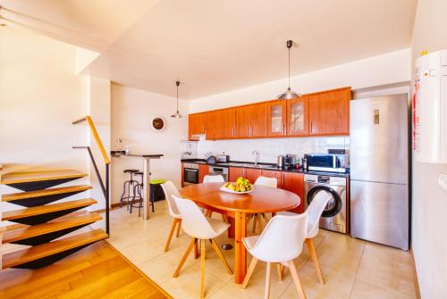a kitchen with a wooden table and white chairs at Madeira Offline by Amazing Madeira in Ponta Delgada