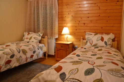 a bedroom with two beds and a table with a lamp at Вила Пенчеви, кк. Цигов чарк in Tsigov Chark