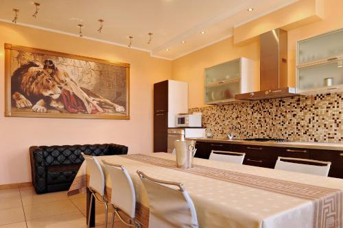 eine Küche mit einem Tisch mit Stühlen und einem Gemälde an der Wand in der Unterkunft Raina Lux Apartment in Riga
